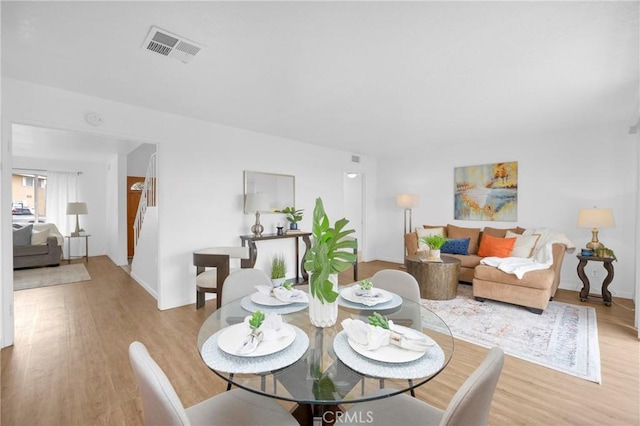 dining space featuring visible vents, baseboards, and light wood finished floors