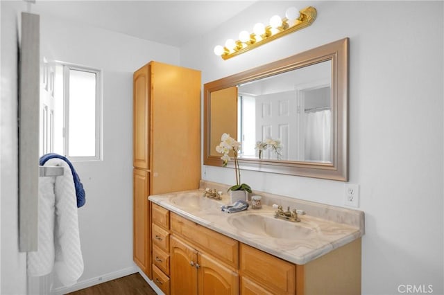 full bathroom with double vanity, baseboards, and a sink