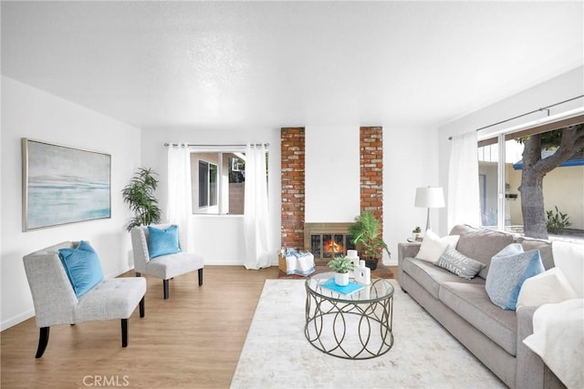 living area with light wood finished floors, a fireplace, and baseboards