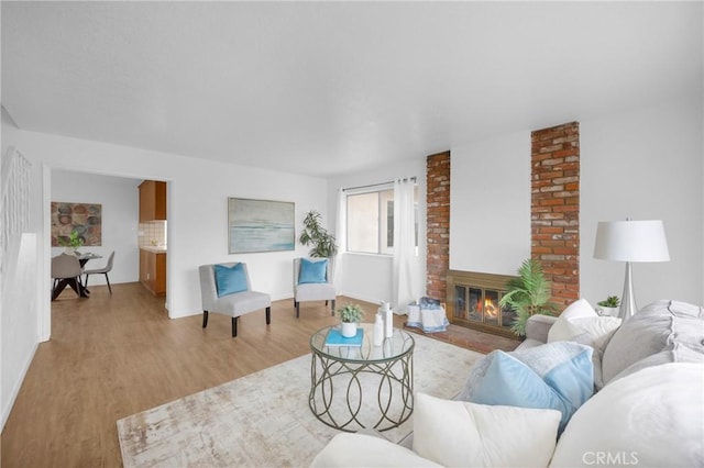 living room featuring light wood-type flooring and a brick fireplace