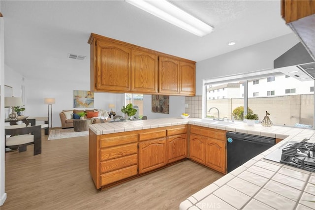 kitchen featuring visible vents, a sink, decorative backsplash, dishwasher, and light wood-type flooring