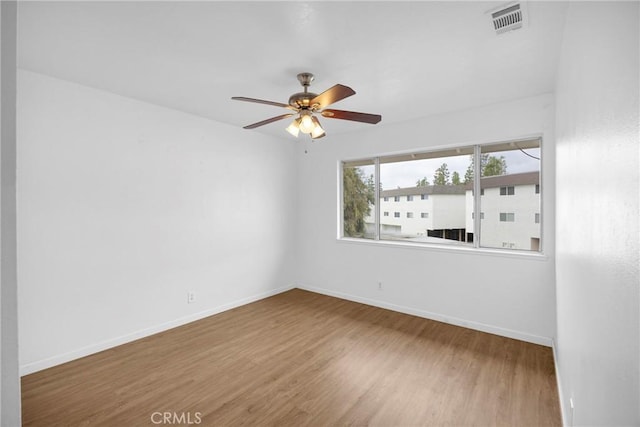 spare room featuring visible vents, ceiling fan, baseboards, and wood finished floors