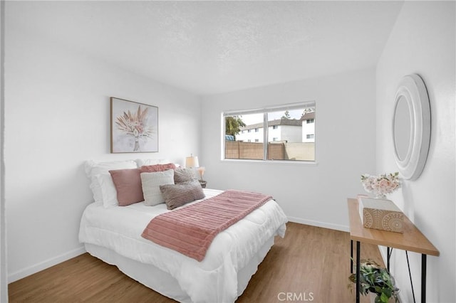 bedroom featuring wood finished floors, baseboards, and a textured ceiling