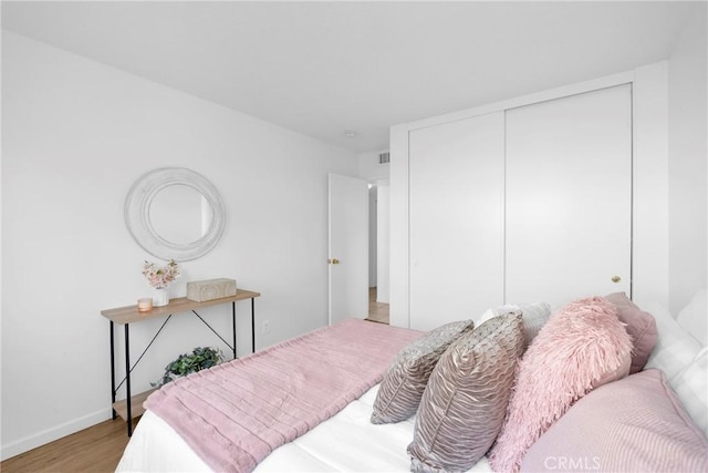 bedroom with a closet, visible vents, baseboards, and light wood-style floors