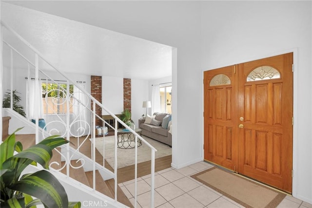 foyer featuring light tile patterned floors, stairs, and baseboards