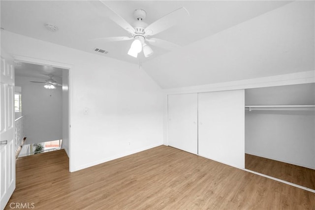 unfurnished bedroom with visible vents, a closet, light wood-style flooring, and vaulted ceiling