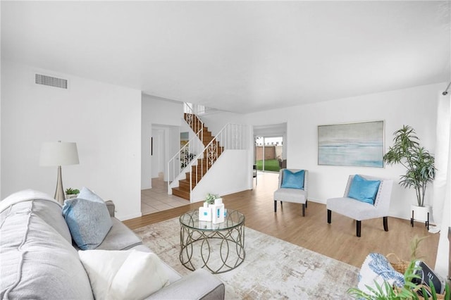 living room with visible vents, wood finished floors, and stairway