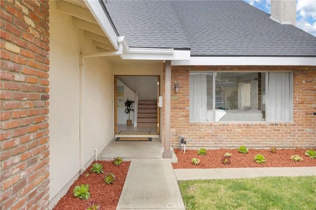 view of exterior entry featuring brick siding and roof with shingles