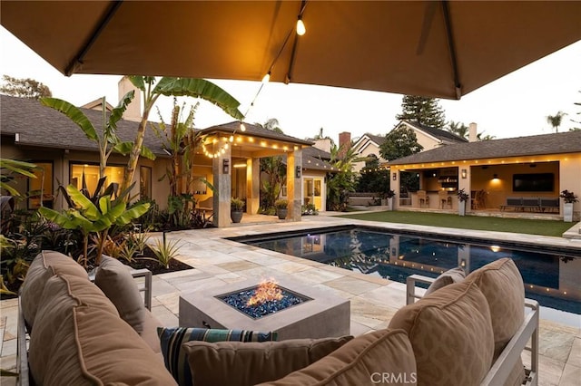 outdoor pool with an outdoor living space with a fire pit, a patio, and area for grilling