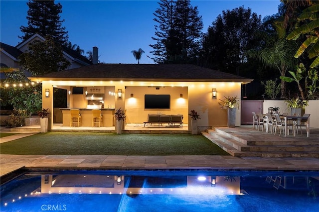 outdoor pool featuring outdoor dry bar, fence, an exterior structure, an outdoor structure, and a patio area