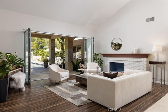 living room with visible vents, high vaulted ceiling, a fireplace, and dark wood-style flooring