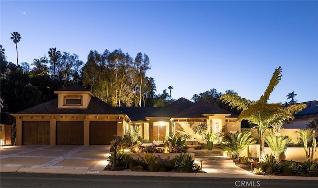 view of front of property featuring stucco siding, driveway, and a garage