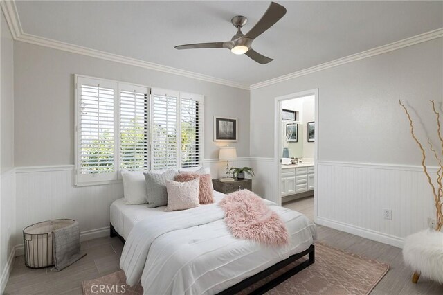 bedroom featuring ornamental molding, a wainscoted wall, and connected bathroom