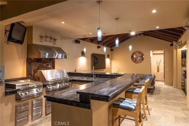 kitchen featuring a breakfast bar, stone finish floor, range hood, decorative backsplash, and lofted ceiling