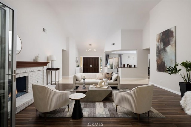 living area with visible vents, high vaulted ceiling, wood finished floors, a fireplace, and baseboards