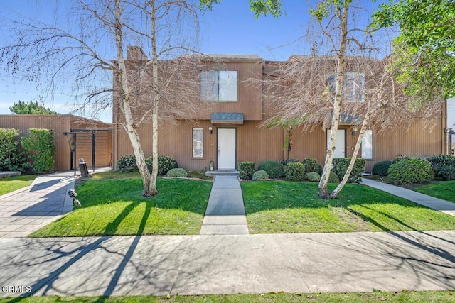 multi unit property featuring a gate, fence, and a front lawn