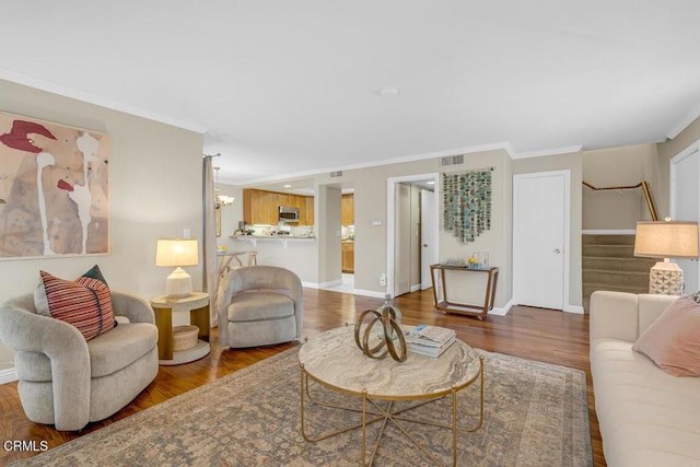 living room featuring baseboards, crown molding, stairway, and wood finished floors