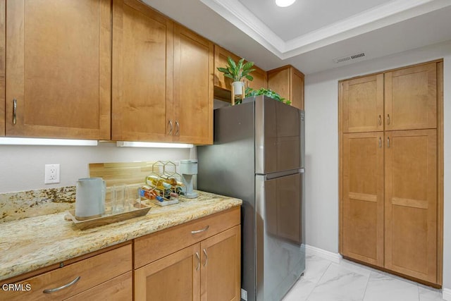 kitchen with visible vents, a raised ceiling, light stone counters, freestanding refrigerator, and marble finish floor