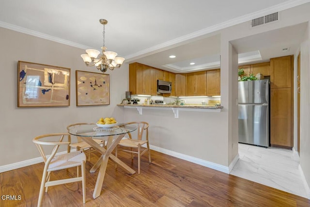 dining room with light wood-type flooring, baseboards, visible vents, and crown molding