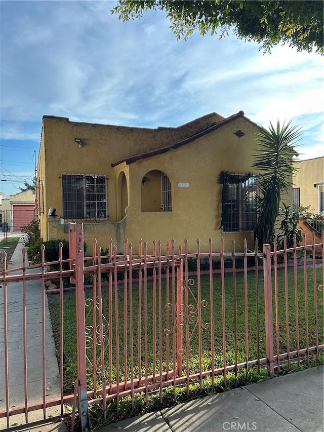 view of front of house featuring fence, a front lawn, and stucco siding