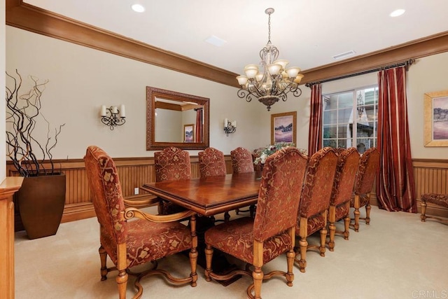 dining room featuring a wainscoted wall, ornamental molding, carpet, and a chandelier