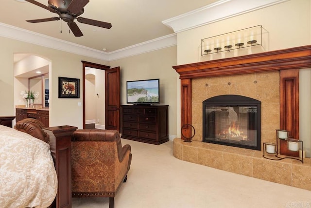 carpeted living area with a ceiling fan, baseboards, crown molding, and a tiled fireplace