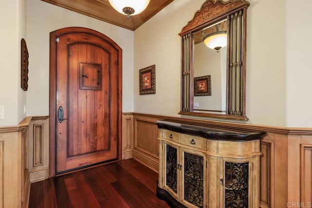 entryway with a wainscoted wall, dark wood-style floors, and crown molding