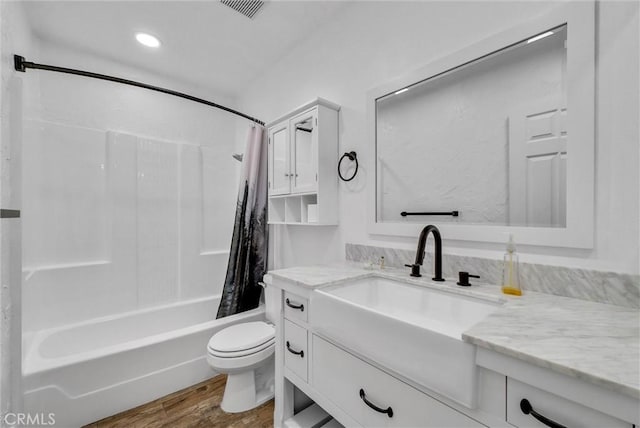 bathroom with toilet, shower / tub combo, wood finished floors, visible vents, and vanity