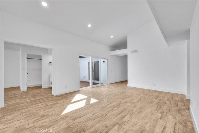 interior space with light wood finished floors, visible vents, baseboards, high vaulted ceiling, and recessed lighting