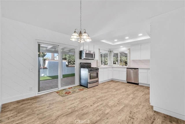 kitchen with stainless steel appliances, white cabinetry, light wood-style floors, light countertops, and an inviting chandelier