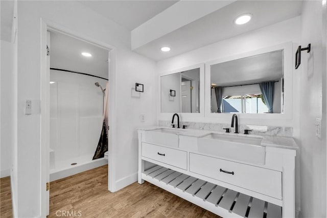 full bath with toilet, a shower with shower curtain, wood finished floors, a sink, and double vanity