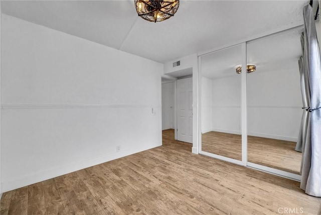 unfurnished bedroom with baseboards, visible vents, and wood finished floors