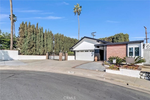 view of front facade featuring driveway, an attached garage, and fence