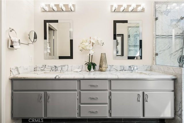 bathroom with a sink, a marble finish shower, and double vanity