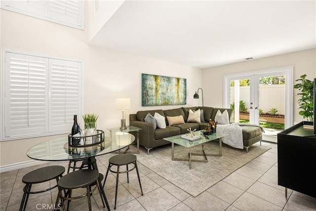 living area with light tile patterned floors, french doors, and baseboards