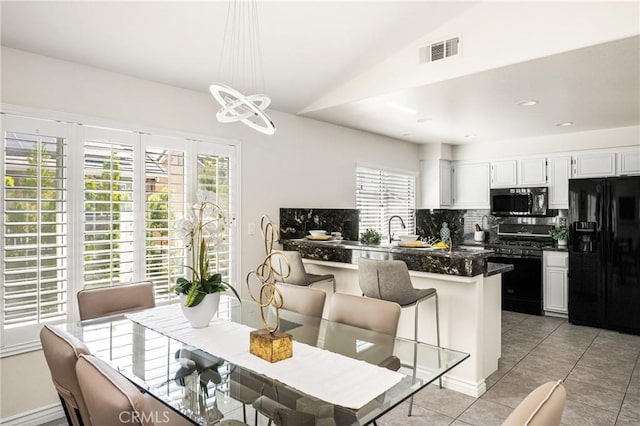 dining area featuring vaulted ceiling, light tile patterned floors, visible vents, and a chandelier