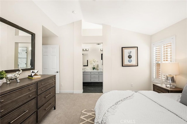 bedroom with vaulted ceiling, light colored carpet, baseboards, and ensuite bathroom