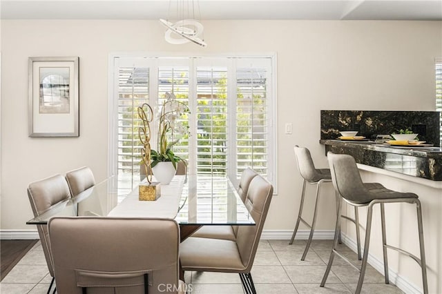 dining area with light tile patterned floors, a healthy amount of sunlight, and baseboards