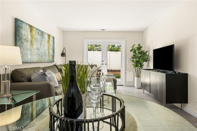 living area featuring visible vents, light tile patterned floors, french doors, and baseboards