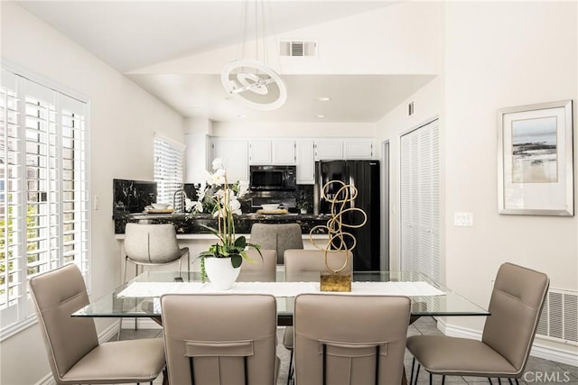 dining room with a chandelier, visible vents, a healthy amount of sunlight, and lofted ceiling