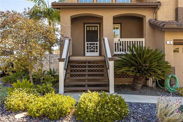 entrance to property featuring covered porch and stucco siding