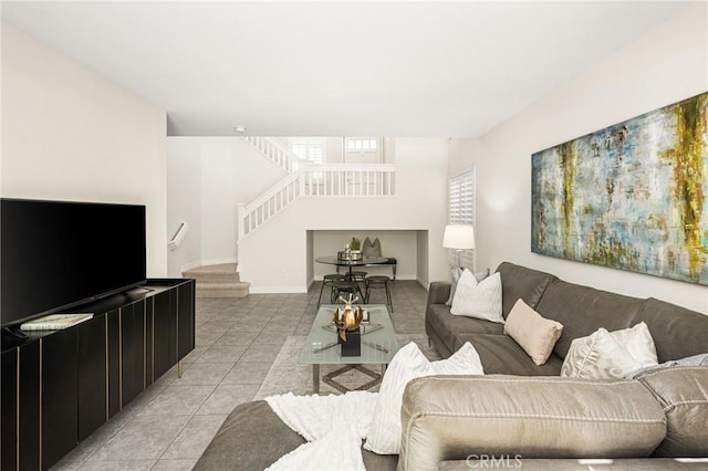 living room with light tile patterned floors, baseboards, and stairs