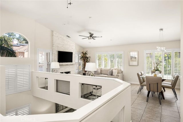 living area featuring visible vents, baseboards, lofted ceiling, light tile patterned floors, and a ceiling fan