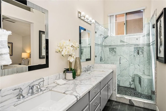 full bath with a marble finish shower, double vanity, and a sink