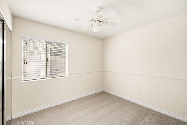 unfurnished room with a ceiling fan, baseboards, and light carpet