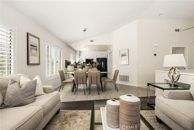 living area featuring visible vents, lofted ceiling, baseboards, and light tile patterned flooring