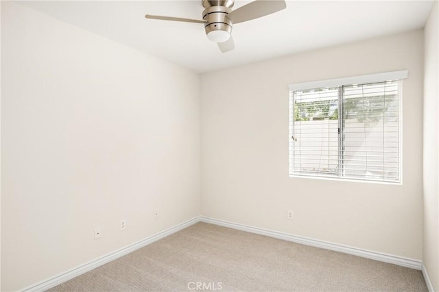 empty room featuring baseboards, light colored carpet, and a ceiling fan