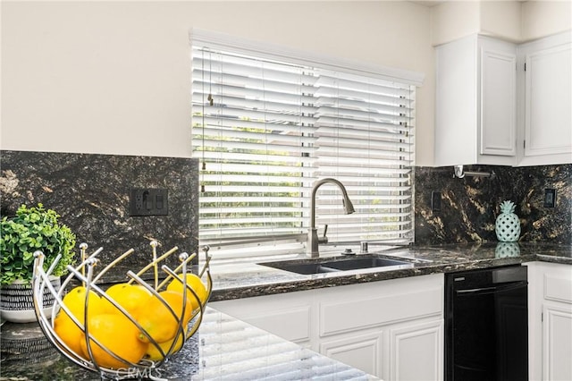 kitchen with a sink, tasteful backsplash, dark stone countertops, and white cabinetry