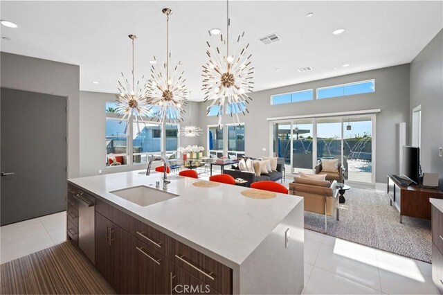 kitchen with light tile patterned flooring, dishwasher, an island with sink, a sink, and open floor plan