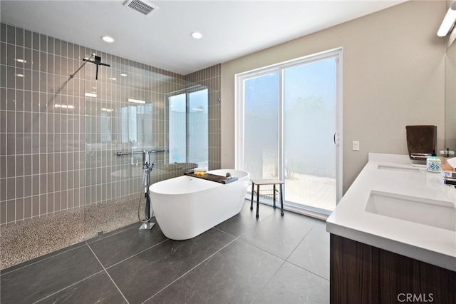 bathroom featuring a walk in shower, a sink, visible vents, a freestanding bath, and double vanity